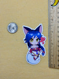 Sticker of an anime-style character with blue hair and fox ears next to a coin and ruler on a beige background