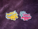 Two colorful dinosaur-shaped stickers on a purple textured surface