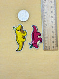 Two colorful stickers resembling a crocodile and an alligator next to a ruler on a beige background