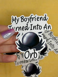 Sticker with text 'My Boyfriend Turned Into An Orb' held by a hand on a yellow background