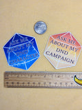 Two hexagonal stickers with text on a beige surface with a ruler for scale.