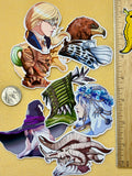 Set of colorful stickers featuring fantasy characters and creatures on a beige background with a ruler for scale.