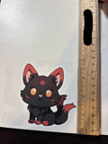 A sticker of a black and red fox kitsune on a white background next to a ruler