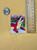 Small colorful sticker of a creature with a ruler for scale on a beige background