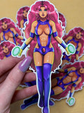 Sticker of the original teen titans Starfire with pink hair and purple outfit held by a hand on a beige background